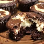 Cheesecake stuffed chocolate cupcakes with creamy centers on a brown plate.