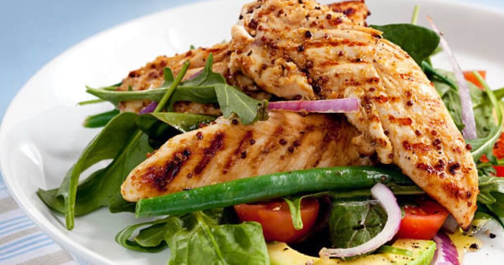 Grilled chicken avocado salad with cherry tomatoes, corn, blue cheese crumbles, and leafy greens.