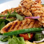 Grilled chicken avocado salad with cherry tomatoes, corn, blue cheese crumbles, and leafy greens.