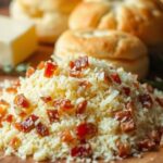 Freshly grated cheese mixed with pancetta bits on a wooden board, with soft biscuits and butter